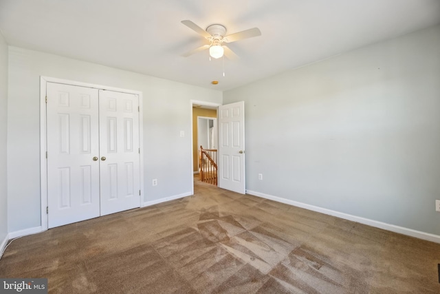 unfurnished bedroom with ceiling fan, a closet, carpet, and baseboards