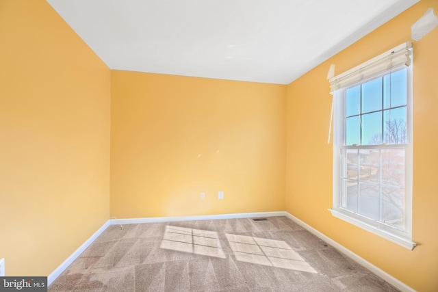 empty room featuring carpet floors, visible vents, and baseboards