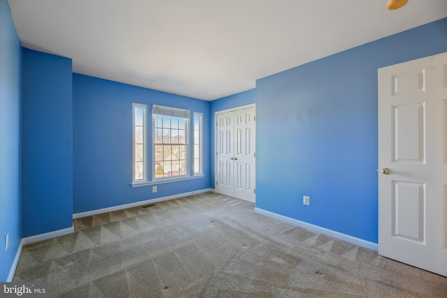 unfurnished bedroom with a closet, carpet flooring, visible vents, and baseboards