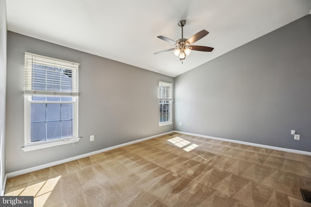 carpeted spare room with a ceiling fan, lofted ceiling, visible vents, and baseboards