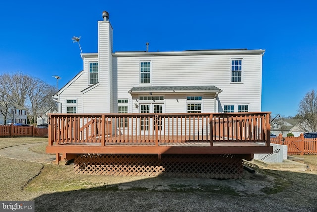 rear view of property featuring a deck, fence, and a chimney