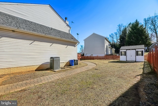 view of yard with central AC, a storage unit, an outdoor structure, and fence