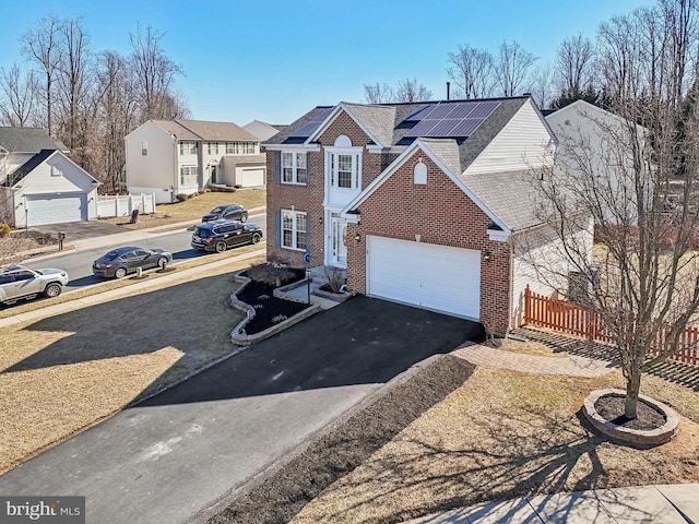 view of front of property with solar panels, brick siding, fence, driveway, and a residential view