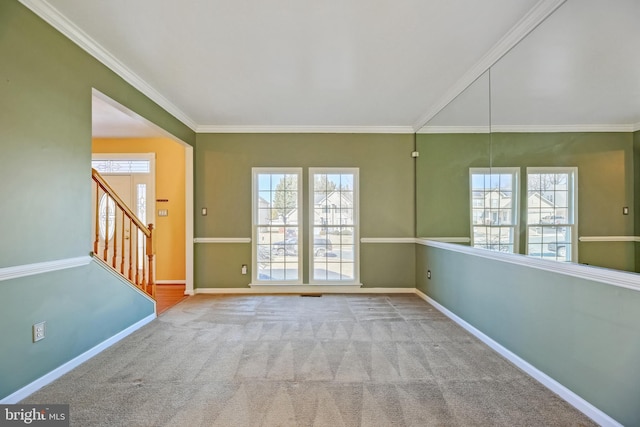 spare room featuring carpet floors, ornamental molding, and baseboards