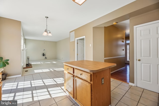 kitchen with light tile patterned floors, a chandelier, open floor plan, light countertops, and pendant lighting