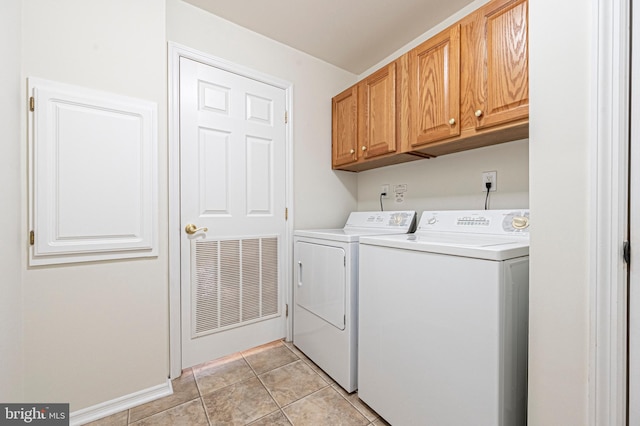 washroom featuring light tile patterned floors, washing machine and dryer, and cabinets