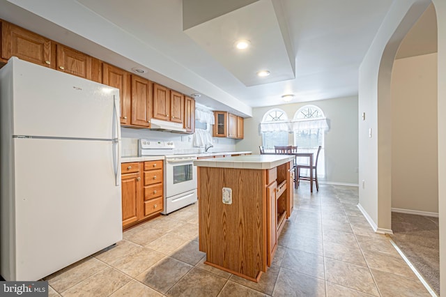 kitchen featuring white appliances, a center island, light carpet, and tile countertops