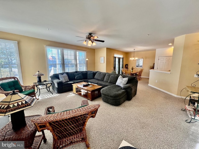 carpeted living room featuring ceiling fan with notable chandelier