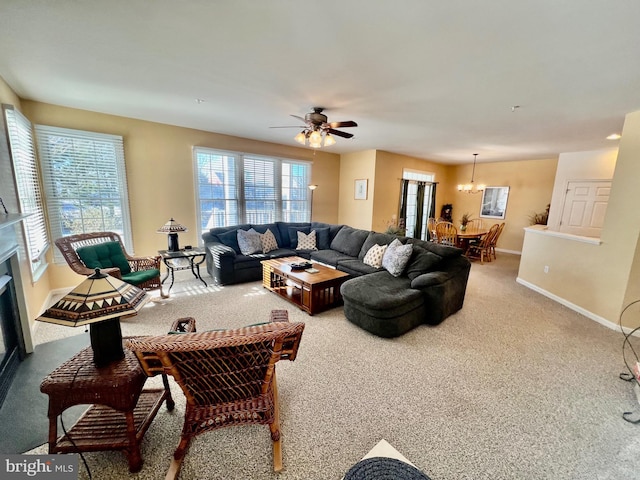 carpeted living room featuring ceiling fan with notable chandelier