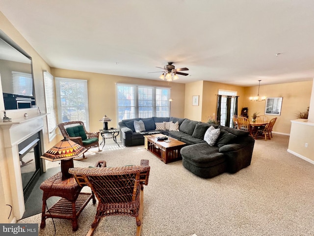 carpeted living room with ceiling fan with notable chandelier