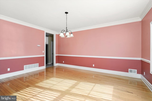 unfurnished room featuring crown molding, hardwood / wood-style flooring, and a notable chandelier