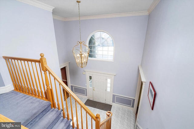 foyer with crown molding and a chandelier