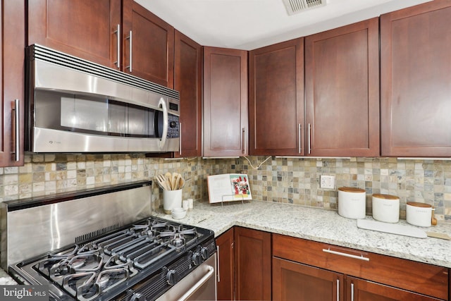 kitchen with light stone counters, stainless steel appliances, and decorative backsplash