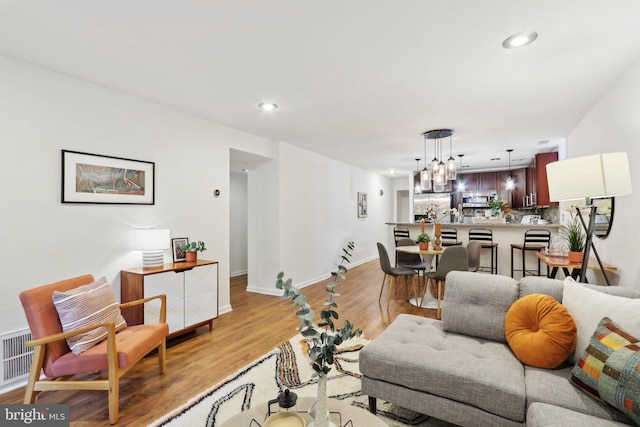 living room featuring a chandelier and light hardwood / wood-style flooring