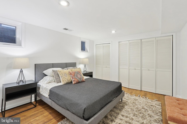 bedroom with hardwood / wood-style flooring and multiple closets