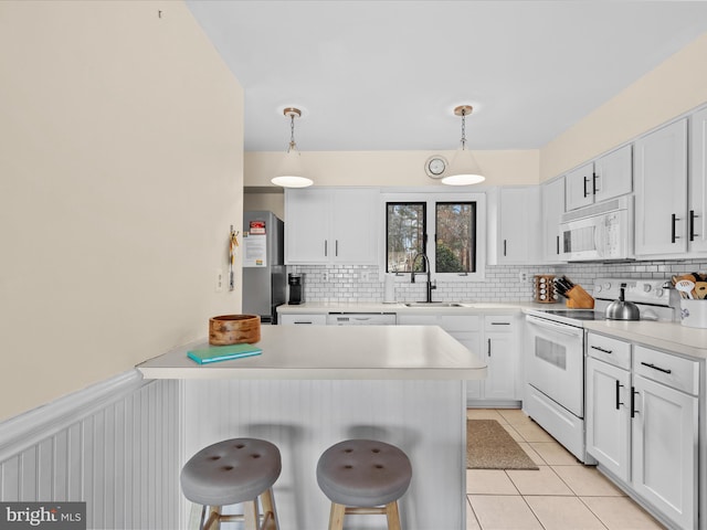 kitchen featuring a kitchen bar, white cabinets, white appliances, and decorative light fixtures