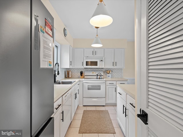 kitchen featuring sink, white appliances, tasteful backsplash, white cabinets, and decorative light fixtures