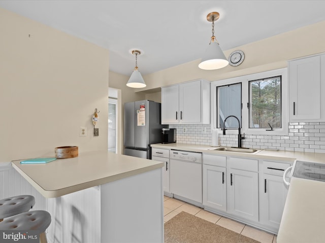 kitchen featuring sink, stainless steel refrigerator, white cabinetry, hanging light fixtures, and white dishwasher