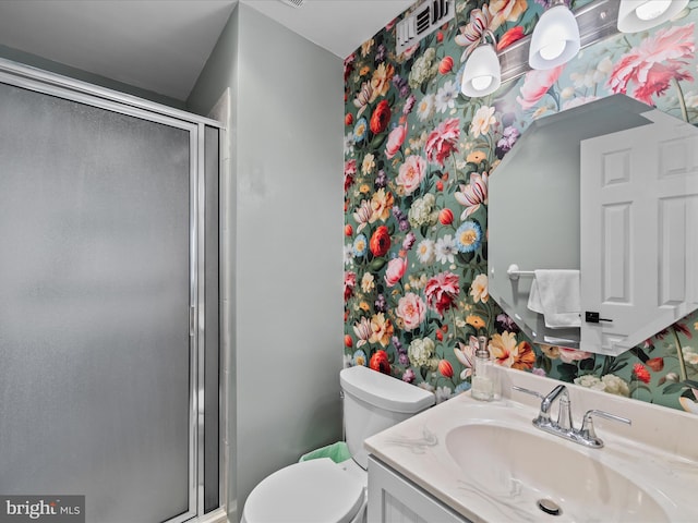 bathroom with a shower with door, vanity, and toilet