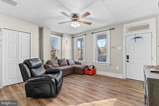 living room featuring ceiling fan, light hardwood / wood-style floors, a textured ceiling, and a wealth of natural light