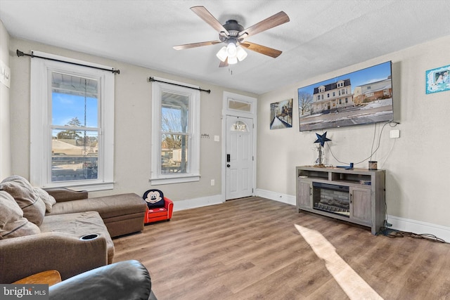 living room with ceiling fan, plenty of natural light, a textured ceiling, and light hardwood / wood-style flooring