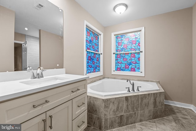 bathroom with tiled tub, tile patterned flooring, and vanity