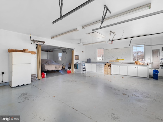 garage with a garage door opener, white refrigerator, and ceiling fan