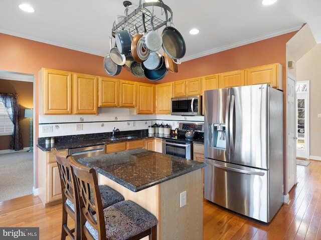 kitchen featuring stainless steel appliances, a kitchen island, dark stone countertops, and ornamental molding