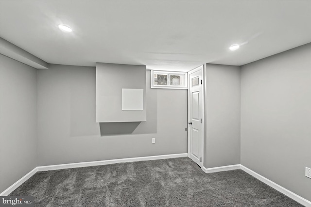 below grade area featuring baseboards and dark colored carpet