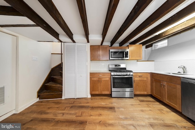 kitchen featuring tasteful backsplash, stainless steel appliances, sink, and light wood-type flooring