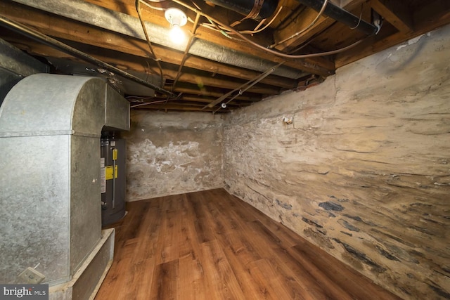 basement with hardwood / wood-style flooring and water heater