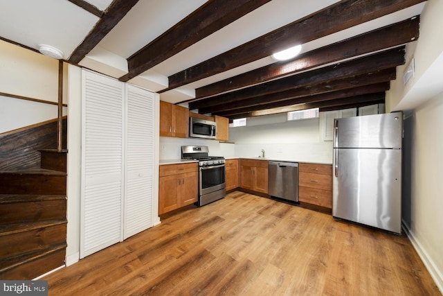 kitchen featuring sink, stainless steel appliances, light hardwood / wood-style floors, and beamed ceiling