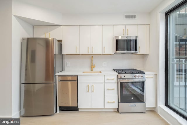 kitchen featuring appliances with stainless steel finishes, sink, white cabinets, and backsplash