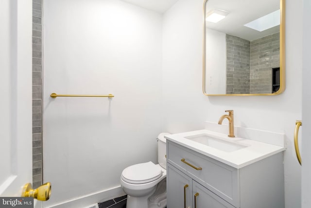 bathroom featuring a skylight, vanity, tile patterned floors, and toilet