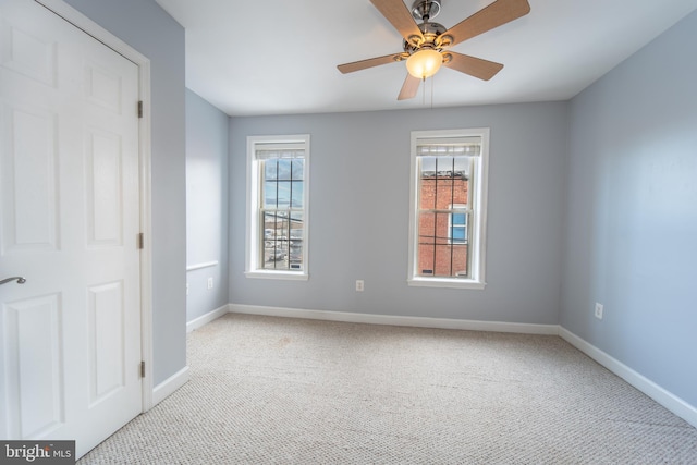 spare room featuring ceiling fan, a healthy amount of sunlight, and light colored carpet