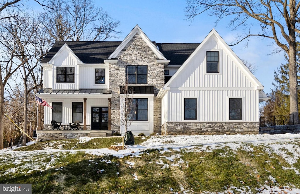 snow covered house with french doors and a porch