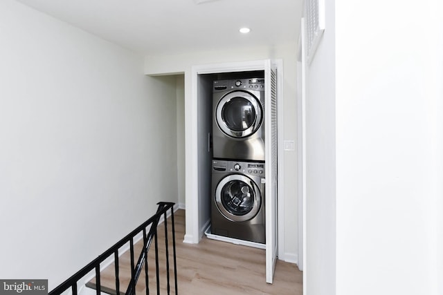 laundry room with stacked washing maching and dryer and light hardwood / wood-style flooring