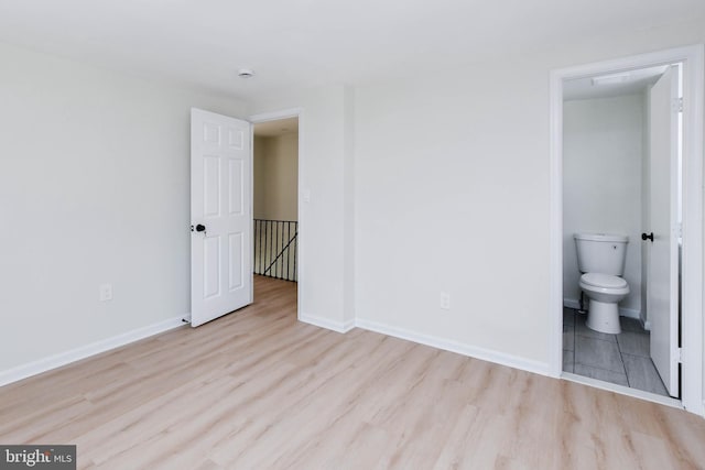 unfurnished bedroom with ensuite bathroom and light hardwood / wood-style floors