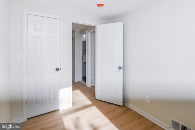 unfurnished bedroom with light wood-type flooring and a closet