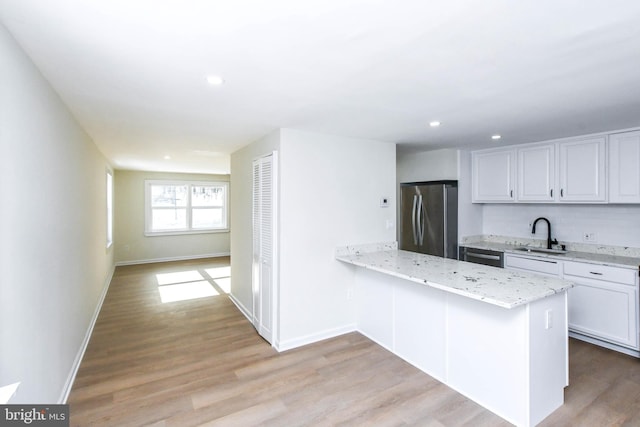 kitchen featuring light wood-type flooring, white cabinetry, kitchen peninsula, and appliances with stainless steel finishes