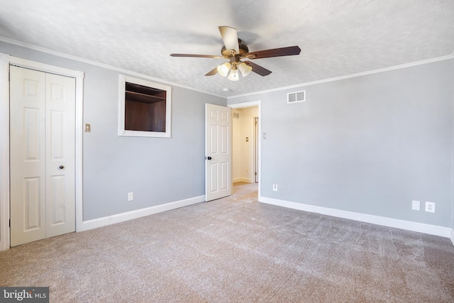 unfurnished bedroom featuring ceiling fan, crown molding, light carpet, and a textured ceiling