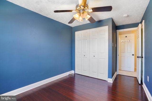 unfurnished bedroom featuring a textured ceiling, a closet, ceiling fan, and dark wood-type flooring