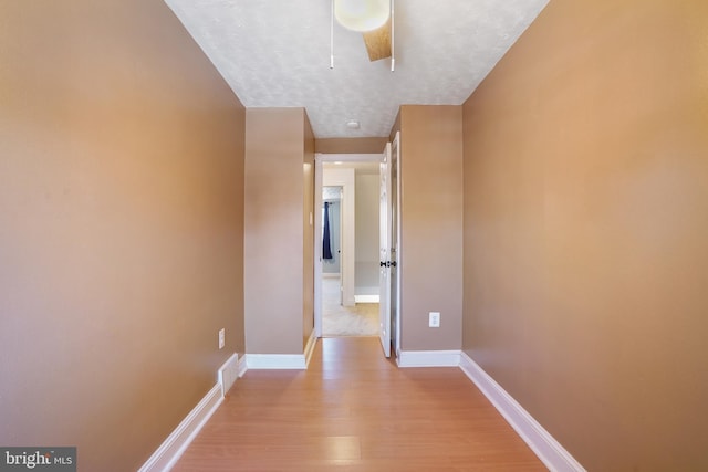 hall featuring a textured ceiling and light hardwood / wood-style flooring