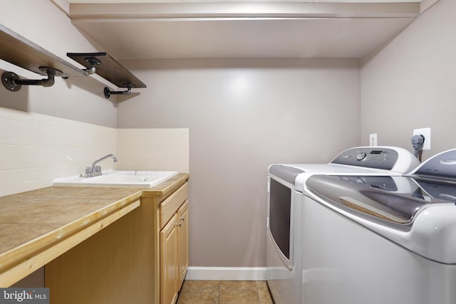 clothes washing area with sink, light tile patterned floors, cabinets, and independent washer and dryer