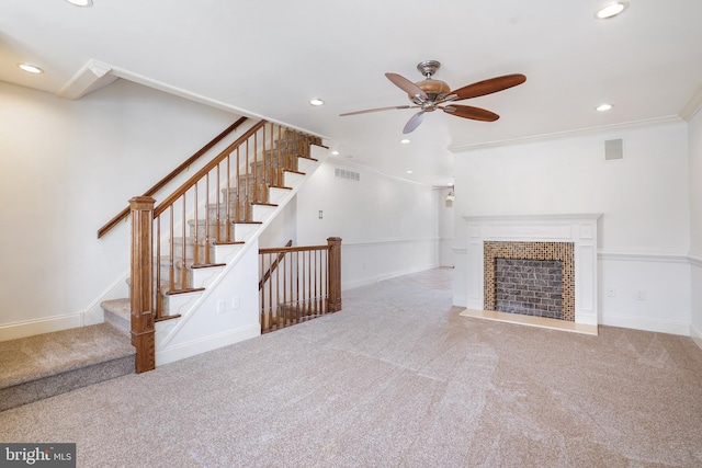 unfurnished living room featuring ceiling fan, a fireplace, crown molding, and light carpet