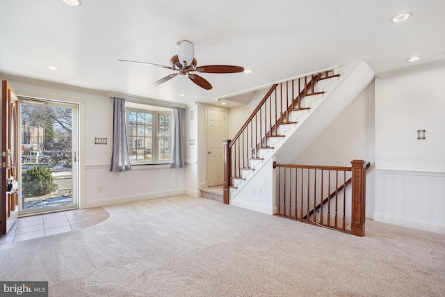 carpeted entryway with ceiling fan and crown molding