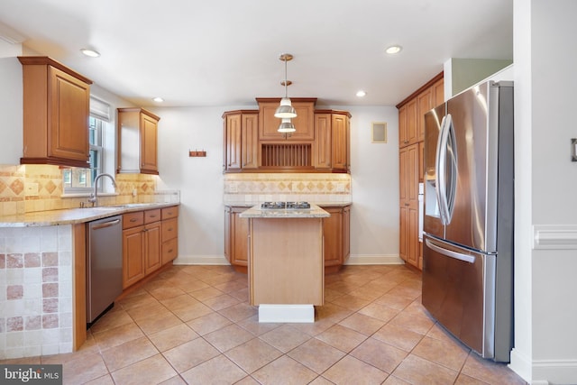 kitchen with sink, light stone countertops, appliances with stainless steel finishes, tasteful backsplash, and a kitchen island