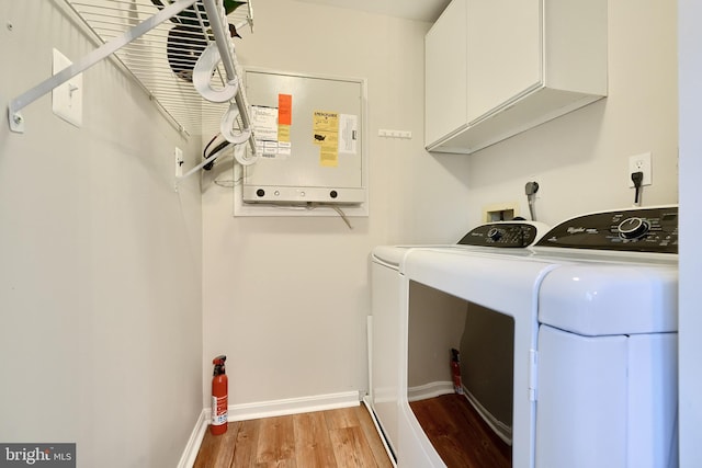 laundry area with separate washer and dryer, light hardwood / wood-style flooring, and cabinets