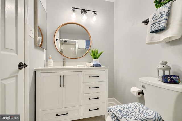 bathroom with a shower with shower door, vanity, and toilet