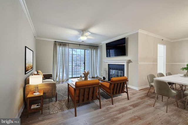 living area featuring ceiling fan, light hardwood / wood-style floors, and crown molding